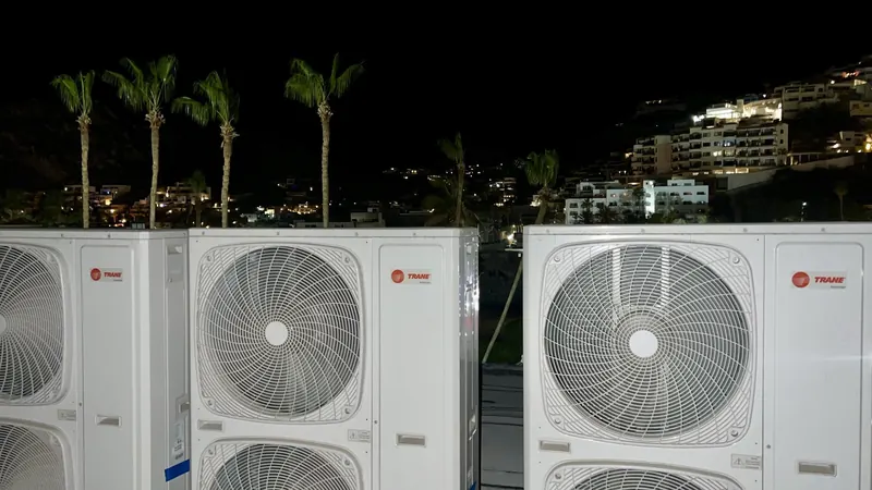 Condensadoras VRF Trane instaladas en azotea de noche, con palmeras y las luces de Cabo San Lucas al fondo